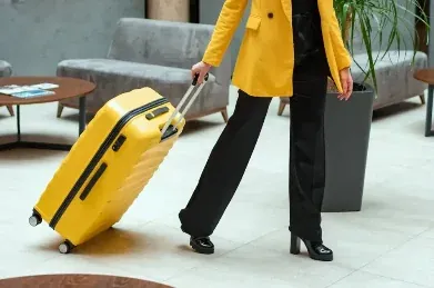 Reisende mit gelbem Koffer im Hotel